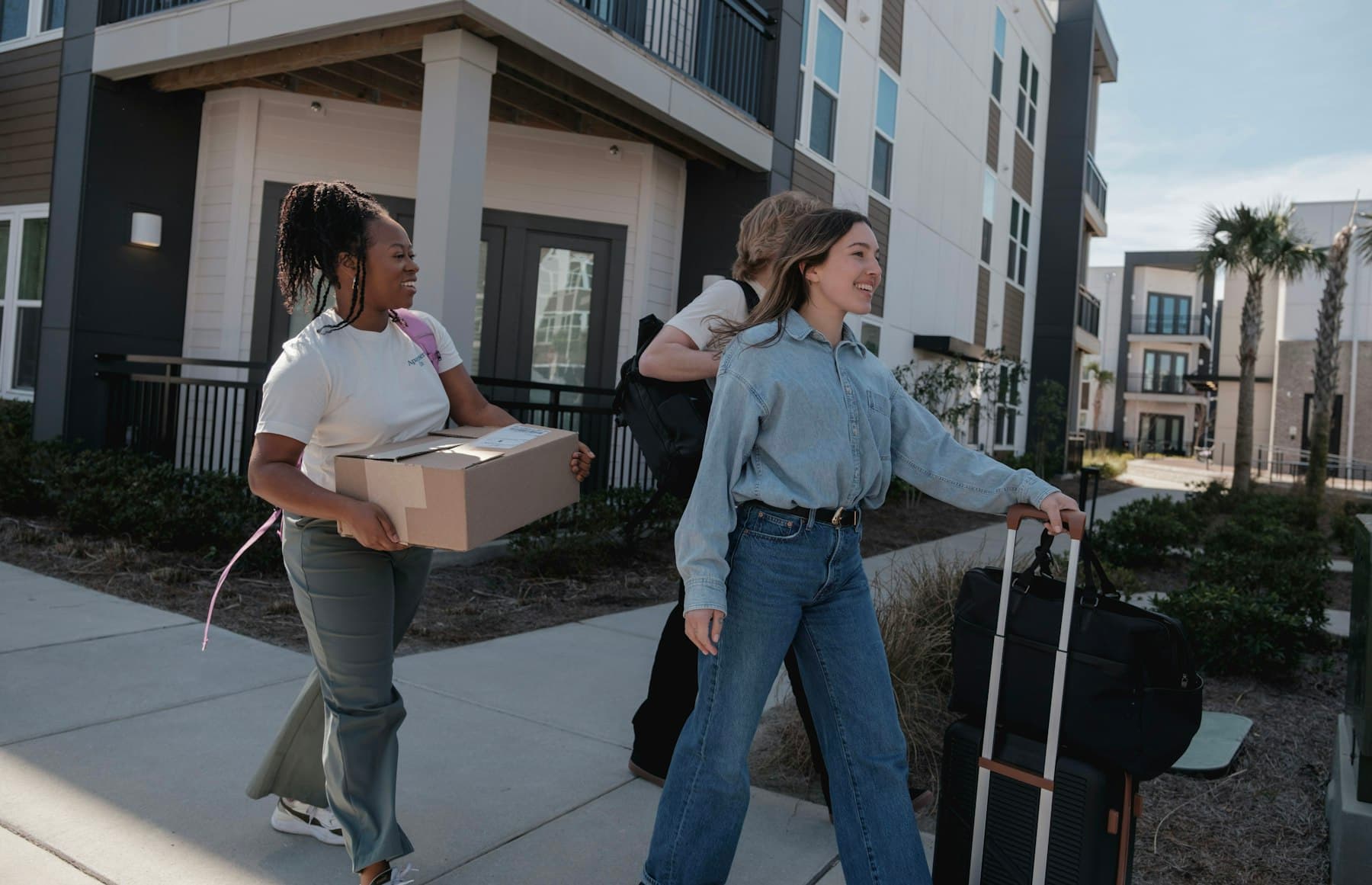 Two residents carrying boxes into their new building