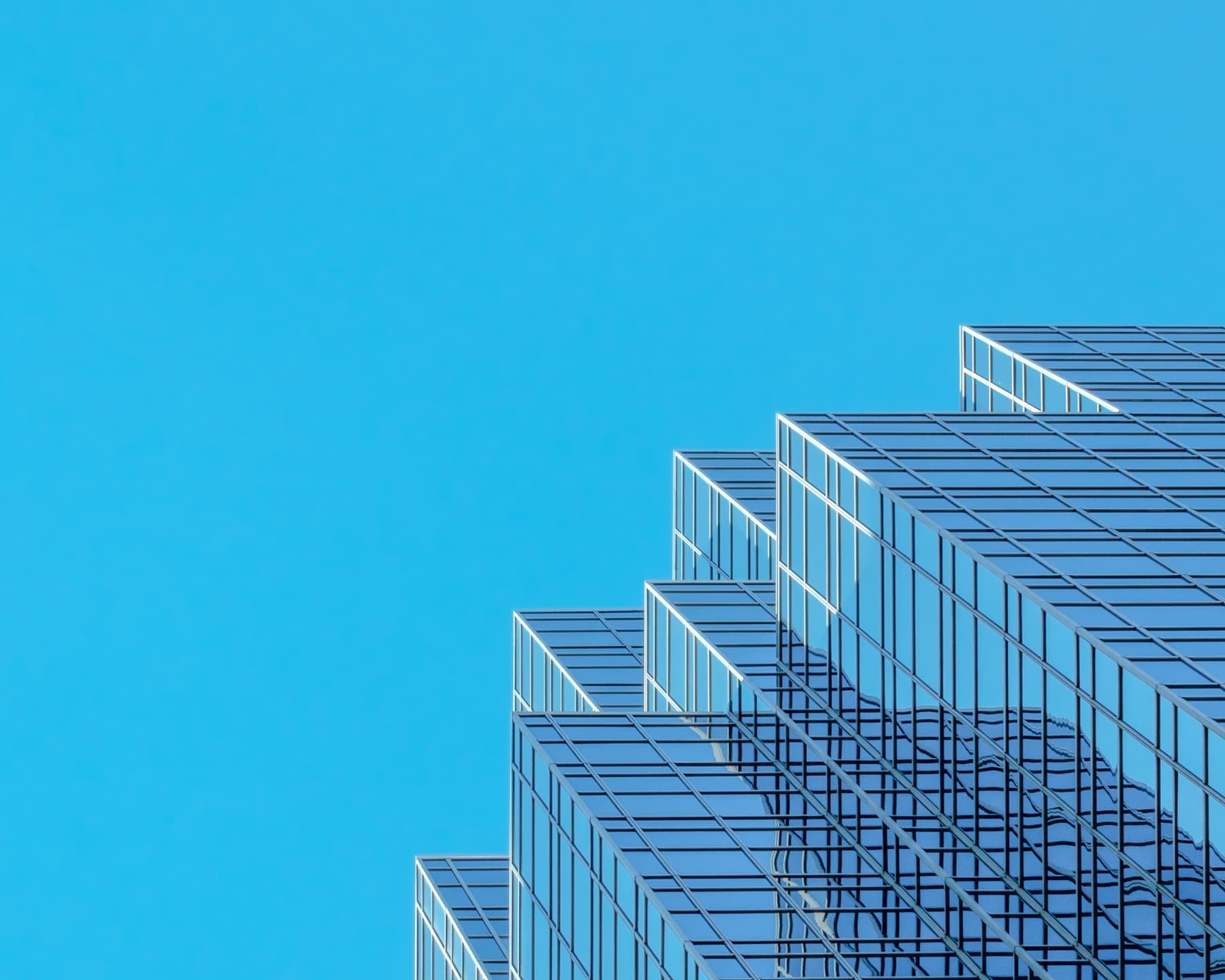 A glass office tower against a blue sky
